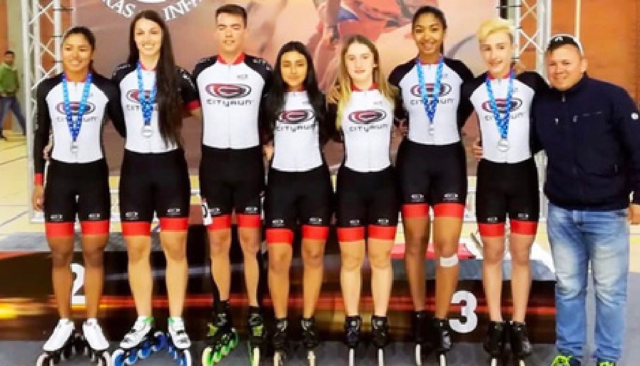 Team Cityrun skaters with medals on the podium and the coach